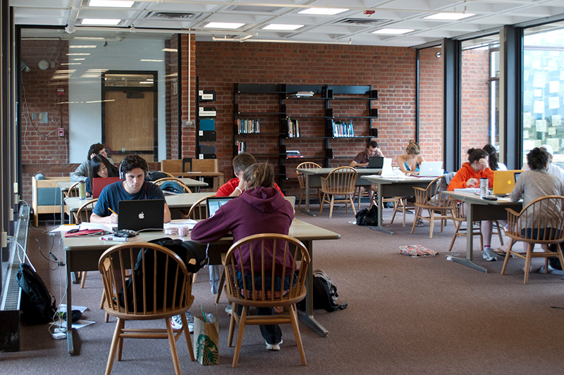 A room containing about 8 tables with 4 chairs each and windows on 2 sides