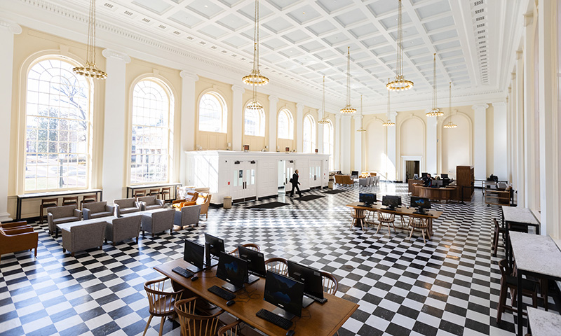 Wide lens view showing a huge room with light fixtures on long chains hanging from a high ceiling, black and white checkered floors, and a variety of seating options.