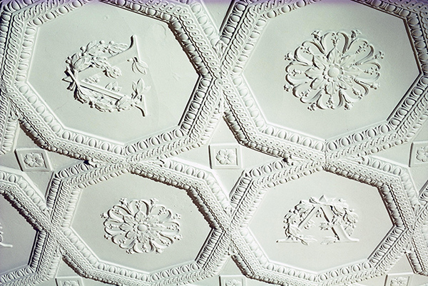 Textured ceiling tiles with octagons and floral patterns, some containing the letter V.