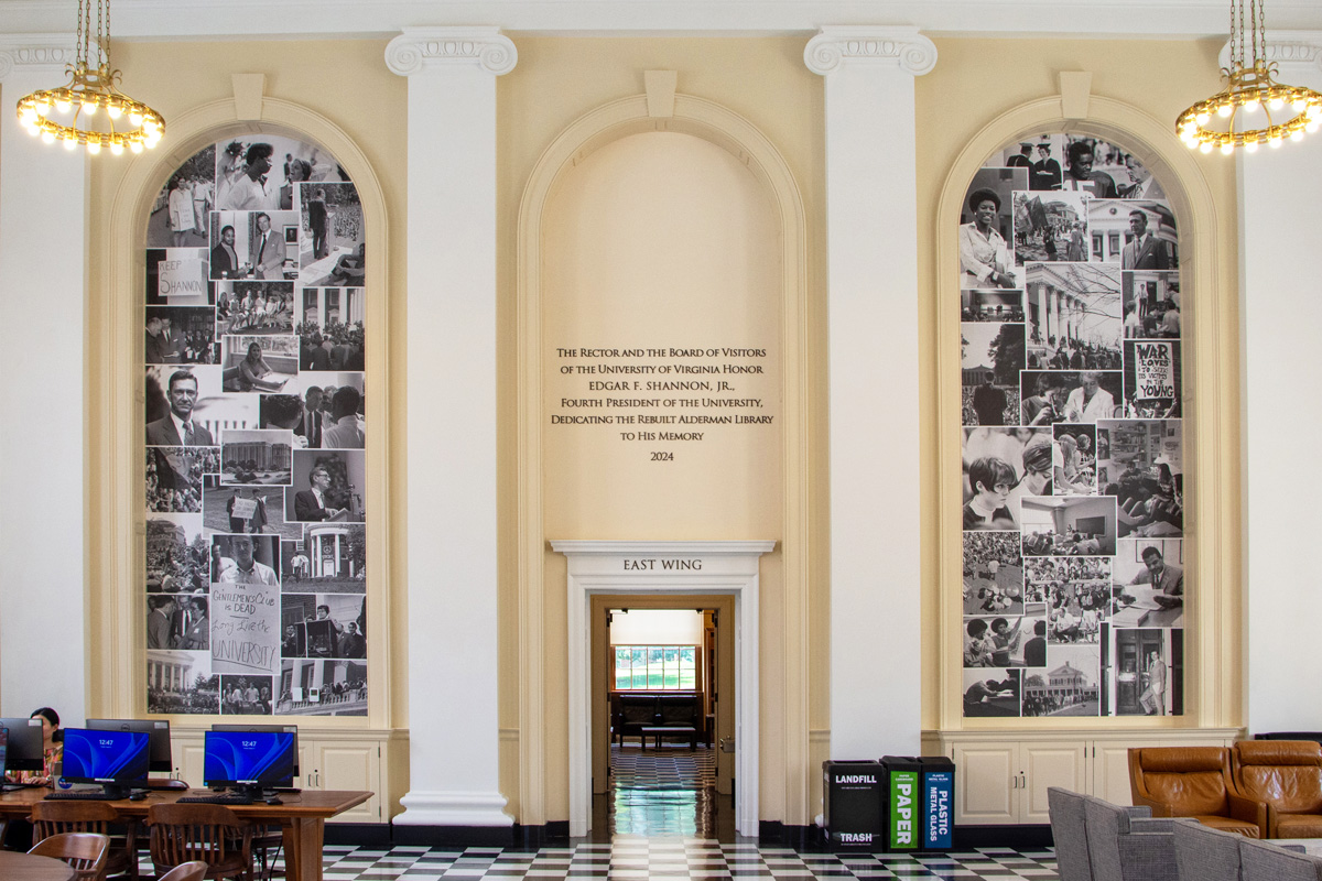 Interior of Memorial Hall in Shannon Library at the University of Virginia, featuring elegant archways, decorative ceiling lights, and large collages of black and white historical photos on the walls.