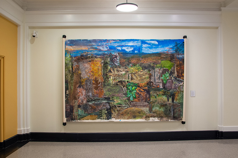 Large, colorful landscape painting displayed on a light-colored wall within a room.