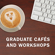 A cup of coffee with 'Graduate Café' written on the foam, next to a computer keyboard on a wooden surface. Text above reads 'GRADUATE CAFÉS AND WORKSHOPS'.