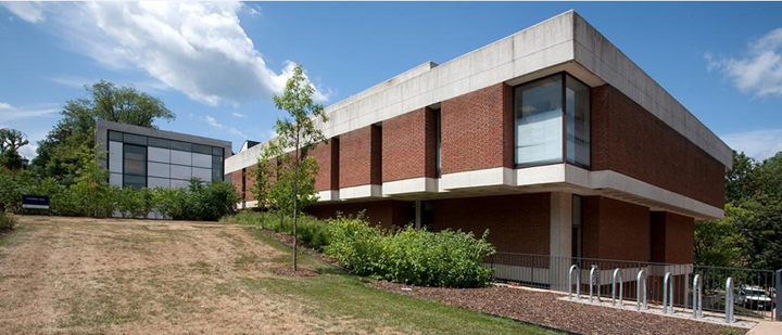 Exterior of Campbell Hall, a rectangular, red brick building against a background of sky and clouds.