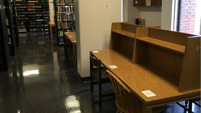 Wooden desk surfaces with shelves for book in back.