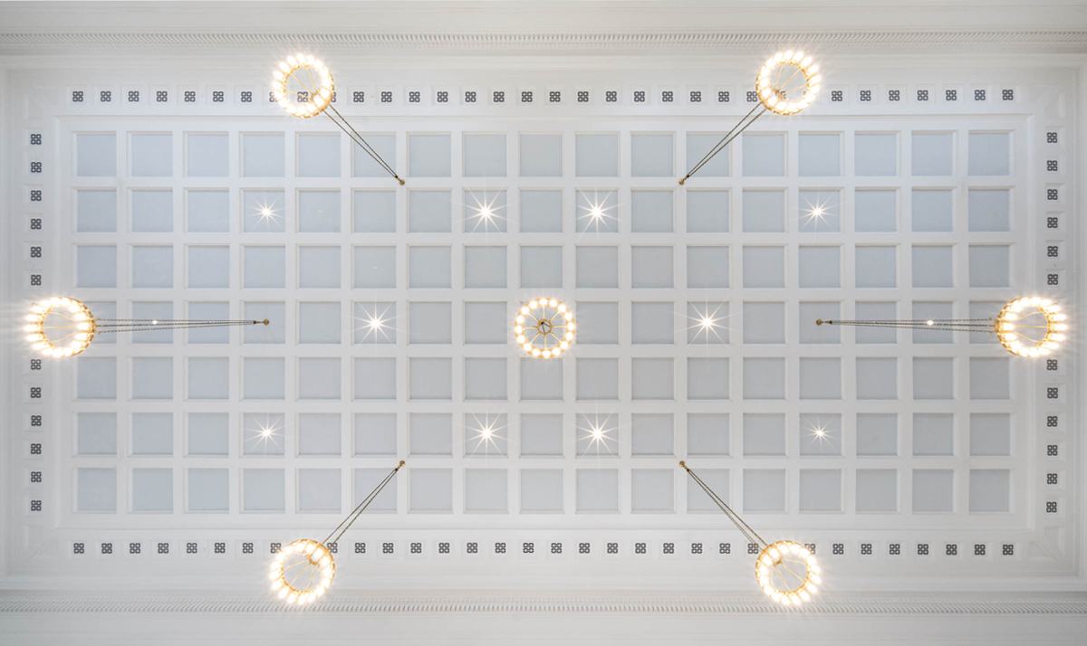 Ceiling view of a geometric light pattern featuring multiple circular chandeliers in a symmetric grid design.