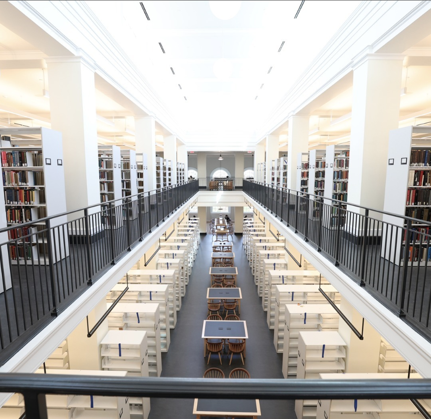 A bright, open space shows a balcony overlooking a lower floor. Both spaces are full of book shelves and natural light.