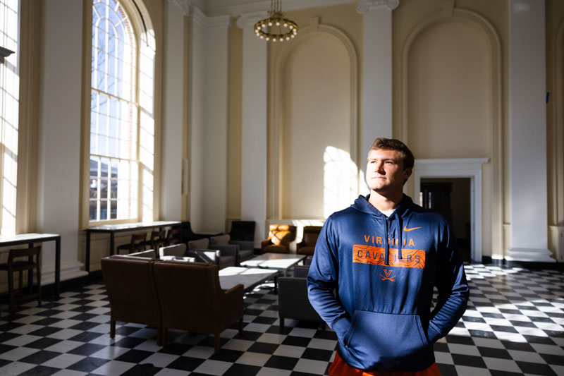 A young man stands in a large lobby with a checkered floor letting the sunlight stream through the windows onto his face.light 