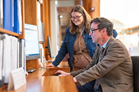 Two people, smiling, look at a computer screen
