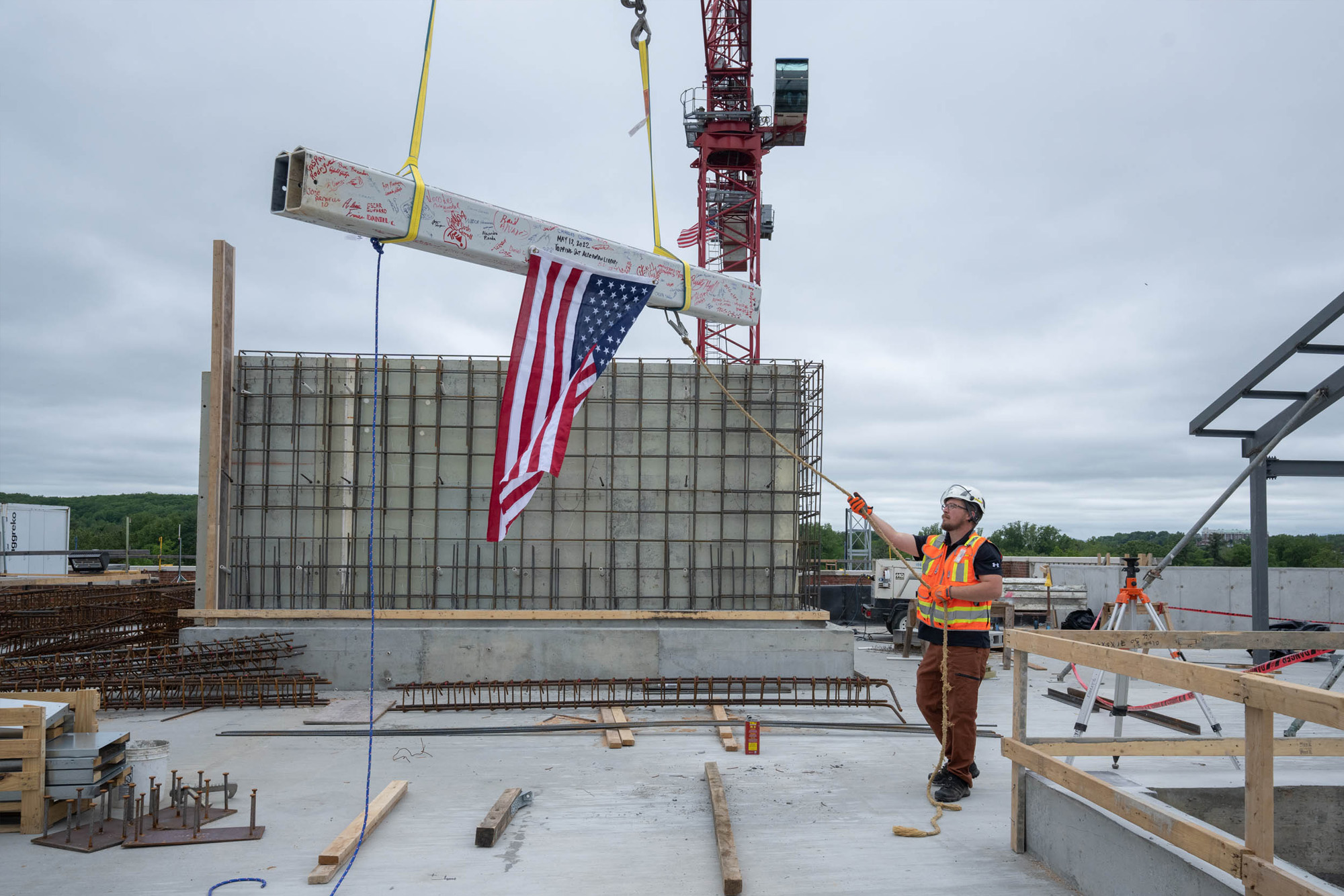 A person in a hard hat pulls a rope tied to a large white beam with varied handwriting all over it