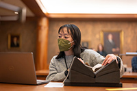 A researcher consults a laptop while looking at a book